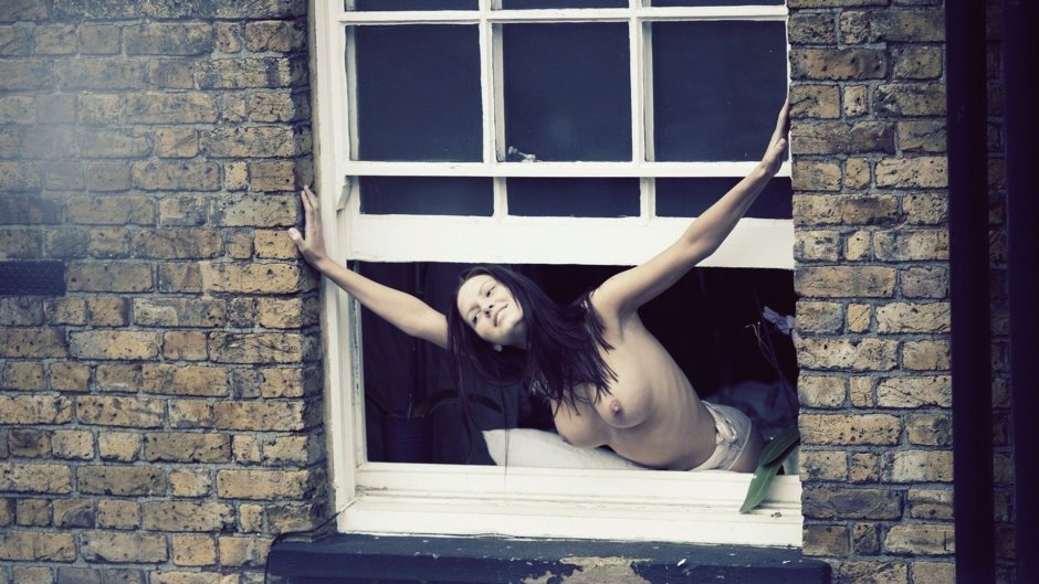 The girl undresses in the window