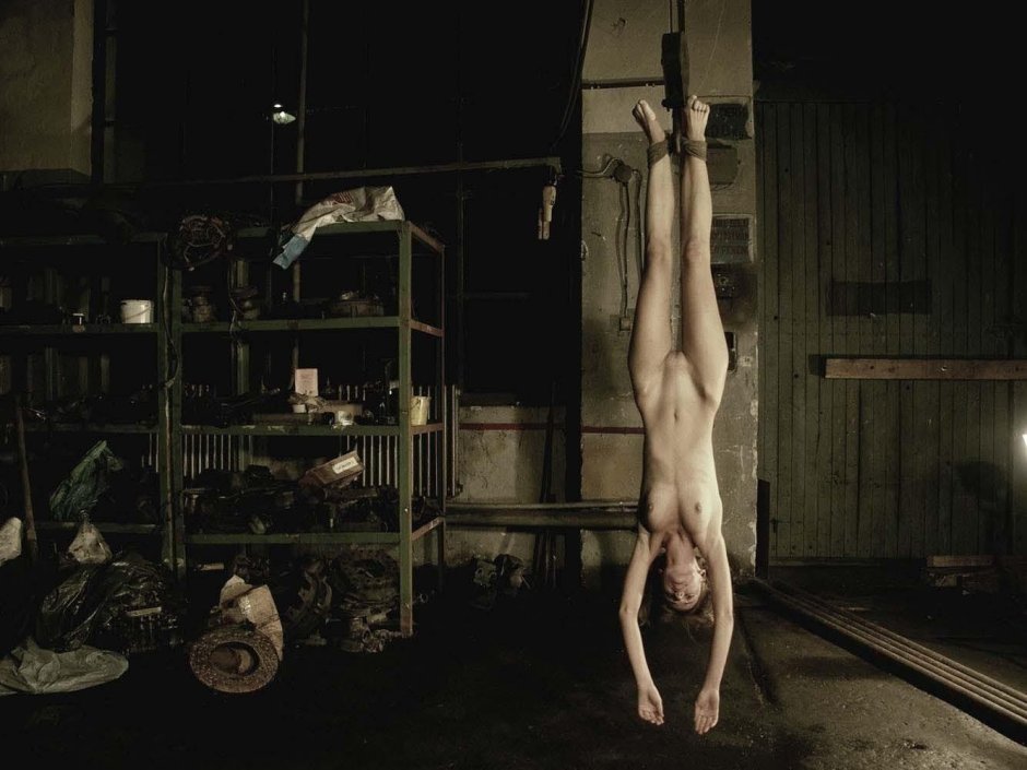 Naked women suspended by their legs