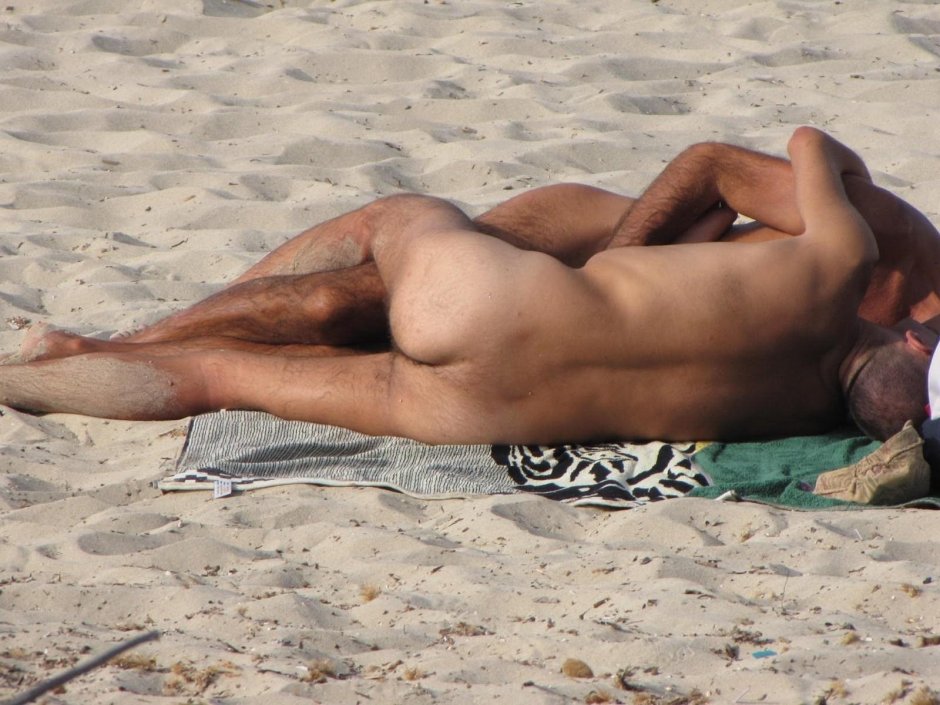 Naked guy lies on the beach